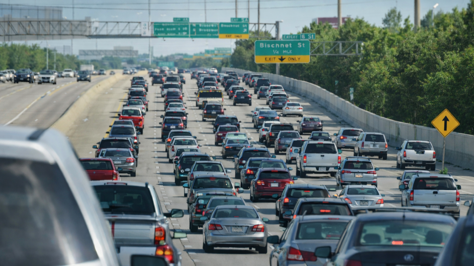 Heavy multi-lane highway traffic with overhead exit signs