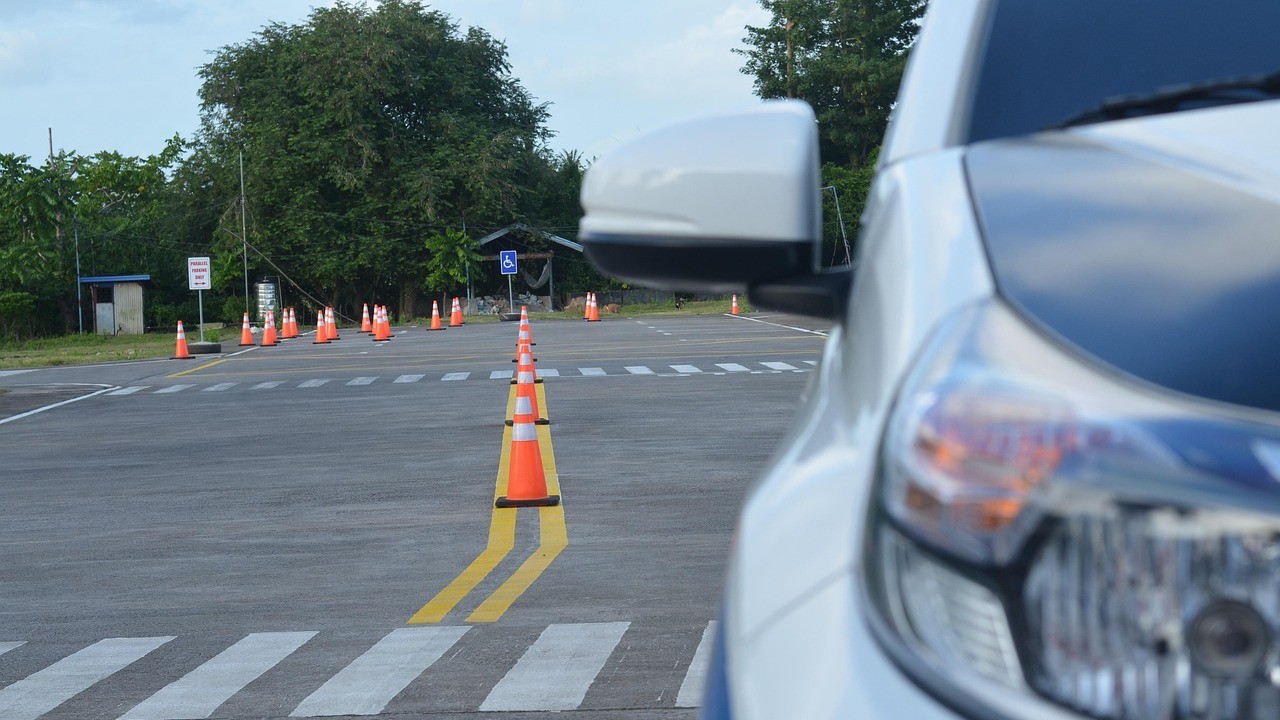 White car parked near traffic cones on a driving test course with a handicap parking sign