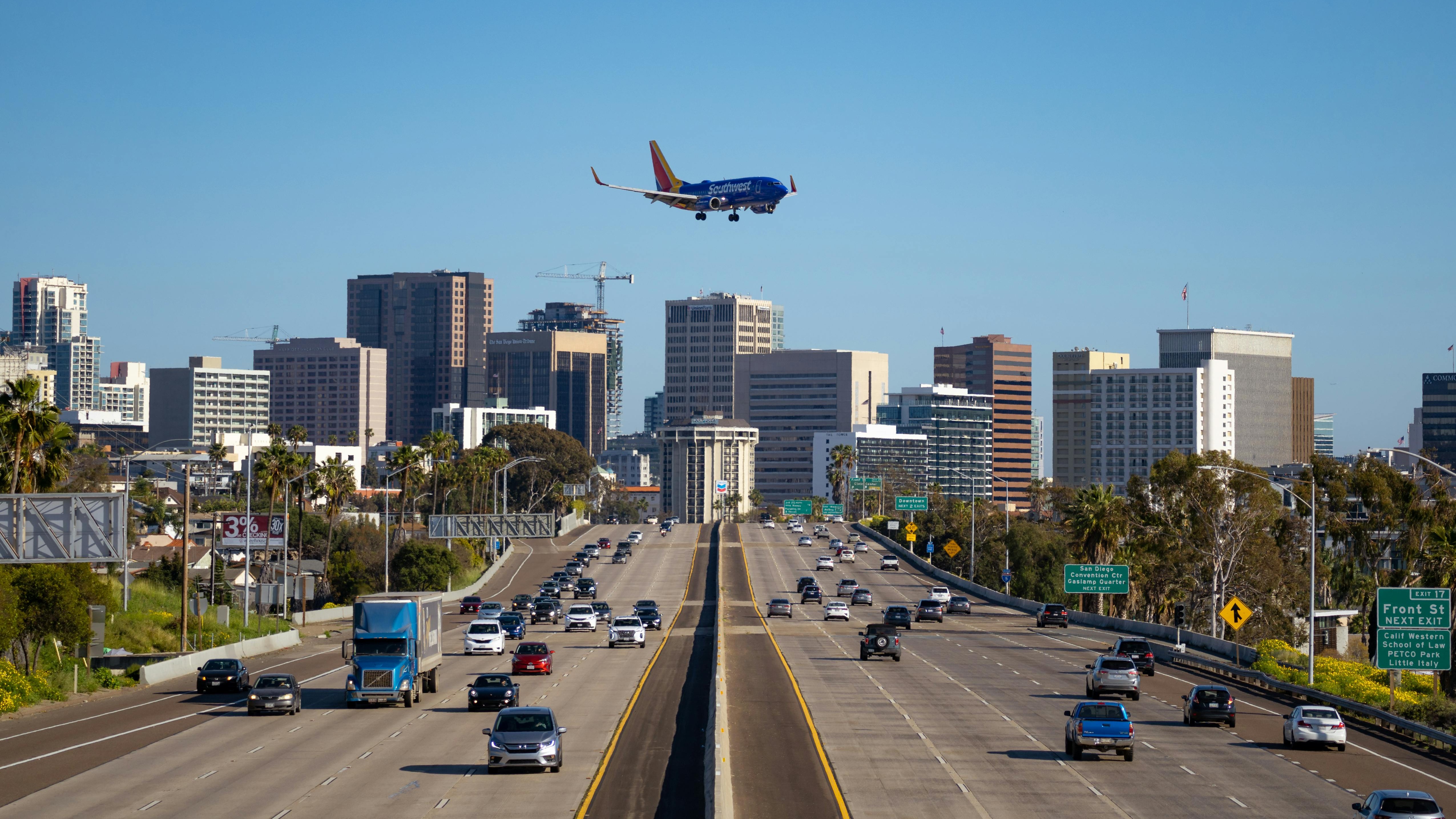 California freeway traffic with a passenger jet landing near the downtown skyline